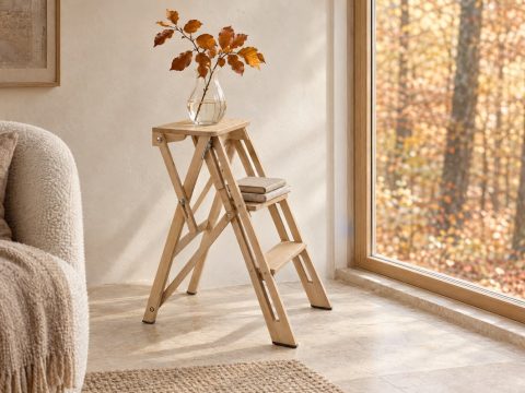 Escalera pequeña de madera de haya usada como mesita junto a una ventana con vistas a un hayedo en otoño